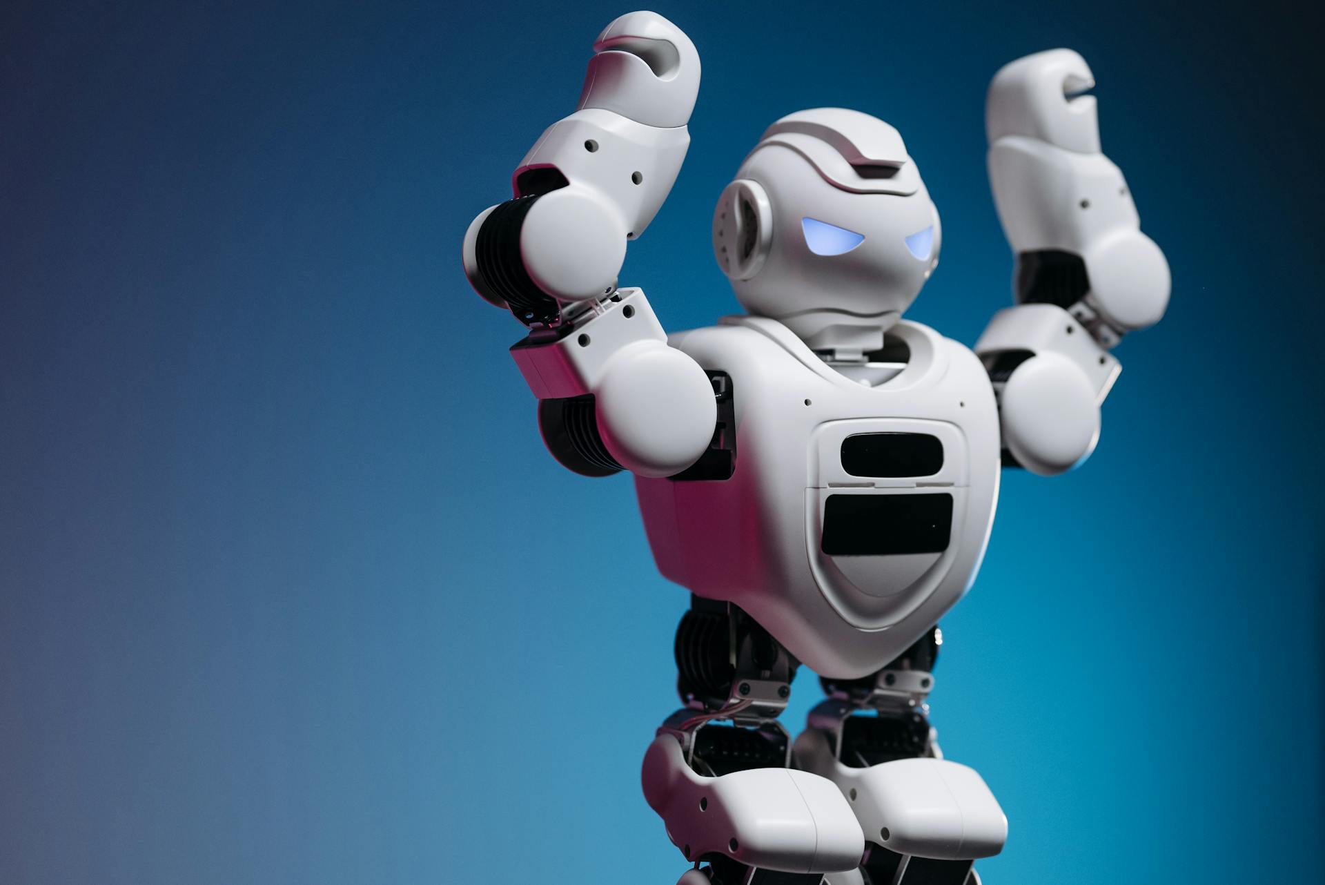 Robot de juguete blanco sobre fondo azul, representando el uso de inteligencia artificial en negocios.